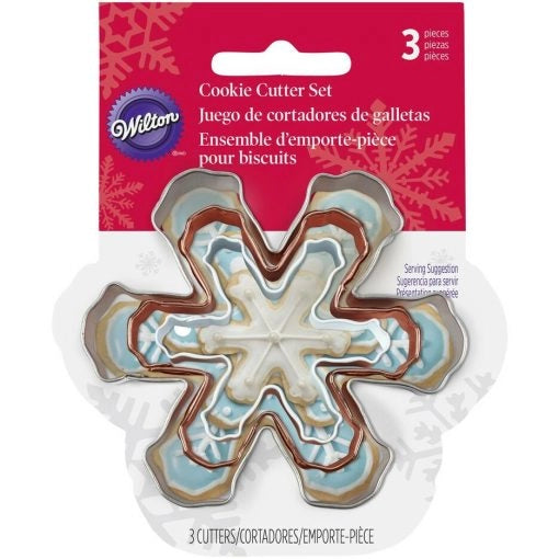 Wilton Cookie Cutter Set met 3 sneeuwvlok koekjesuitstekers in verschillende maten op verpakkingskaart met versierde sneeuwvlok koekjes als voorbeeld