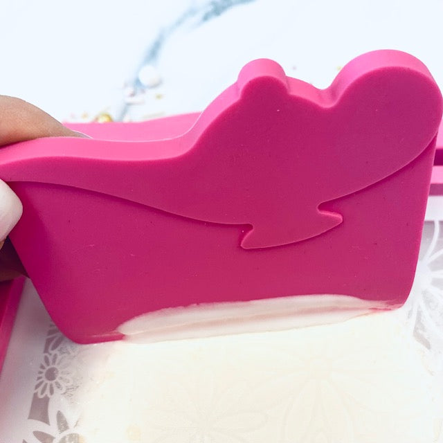 Zijkant van de roze Icing Genie schraper met royal icing op de squeegee-rand