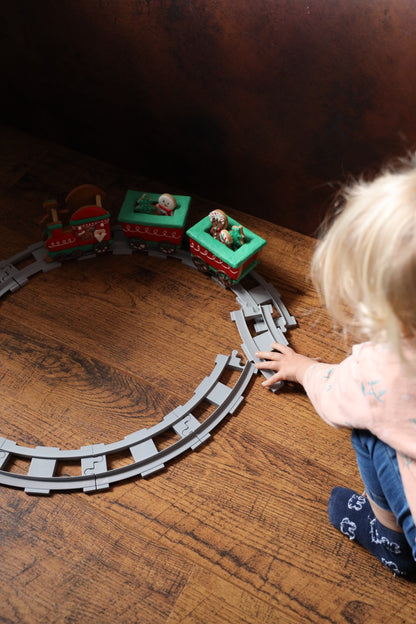 Kind speelt met de 3D kersttrein van koekjes op een cirkel van speelgoedrails