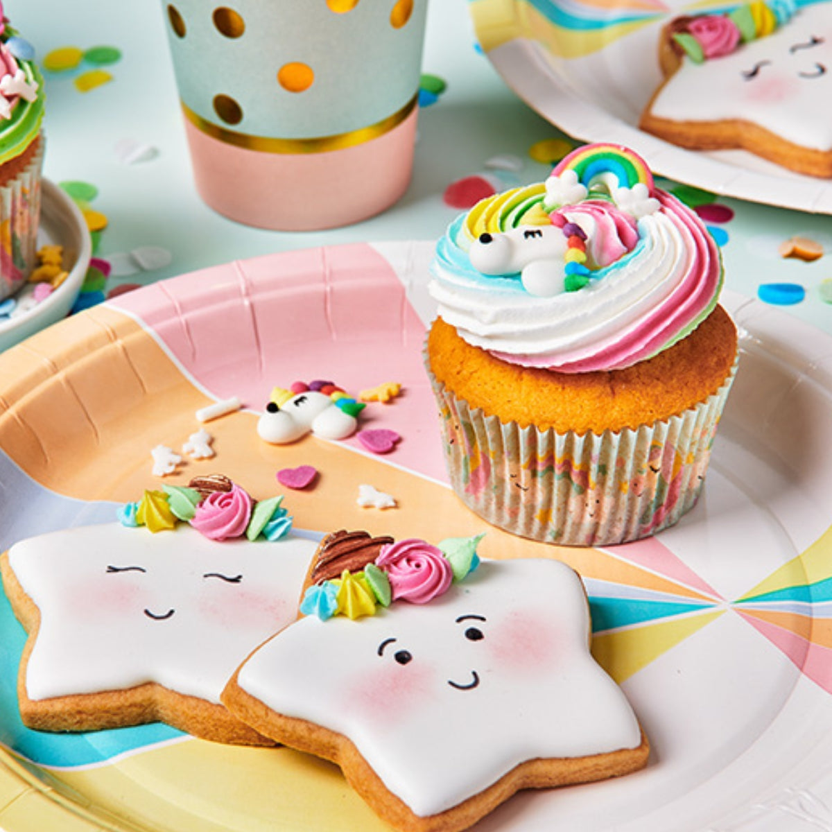 Feestelijke traktatie met FunCakes eenhoorn- en regenboogdecoraties op cupcakes en een koekje