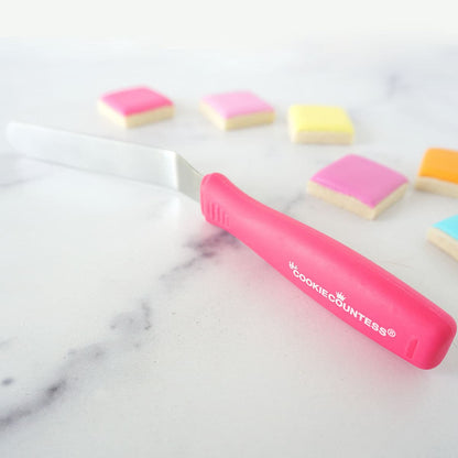 Roze mini offset spatel van The Cookie Countess tussen gedecoreerde koekjes