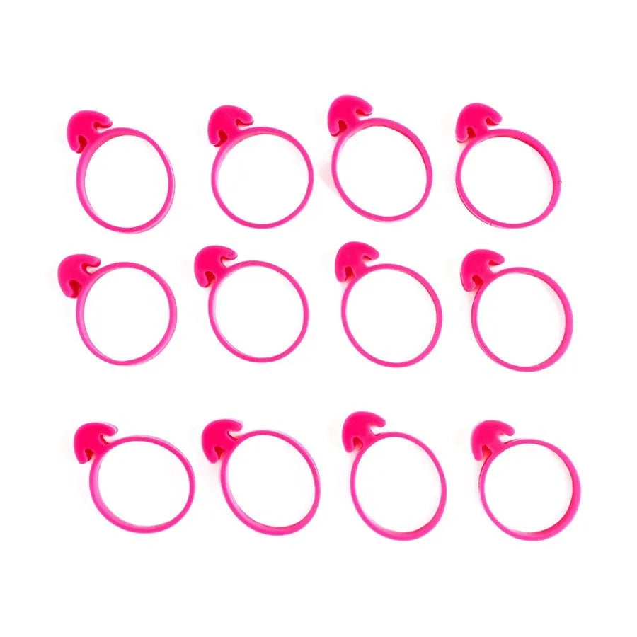 The Cookie Countess Piping Bag Ties set inhoud, 12 roze spuitzakclips uitgelegd op een rij, herbruikbare clips voor het stevig afsluiten van spuitzakken bij het decoreren van koekjes met royal icing