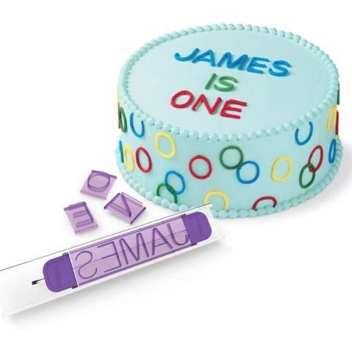 Wilton Numbers/Letters Press Set met paarse stempelhouder en kleurrijke letter- en cijferstempels, getoond met een versierde taart met kleurrijke letters en cijfers, ideaal voor het personaliseren van taarten en koekjes