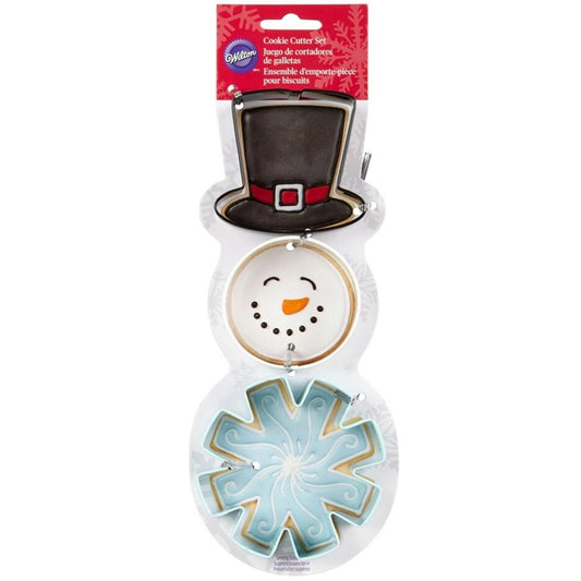 Wilton Snowman Cookie Cutter Set met 3 uitstekers die samen een sneeuwpop vormen: hoge hoed, rond gezichtje en sneeuwvlok, met versierde koekjes als voorbeeld