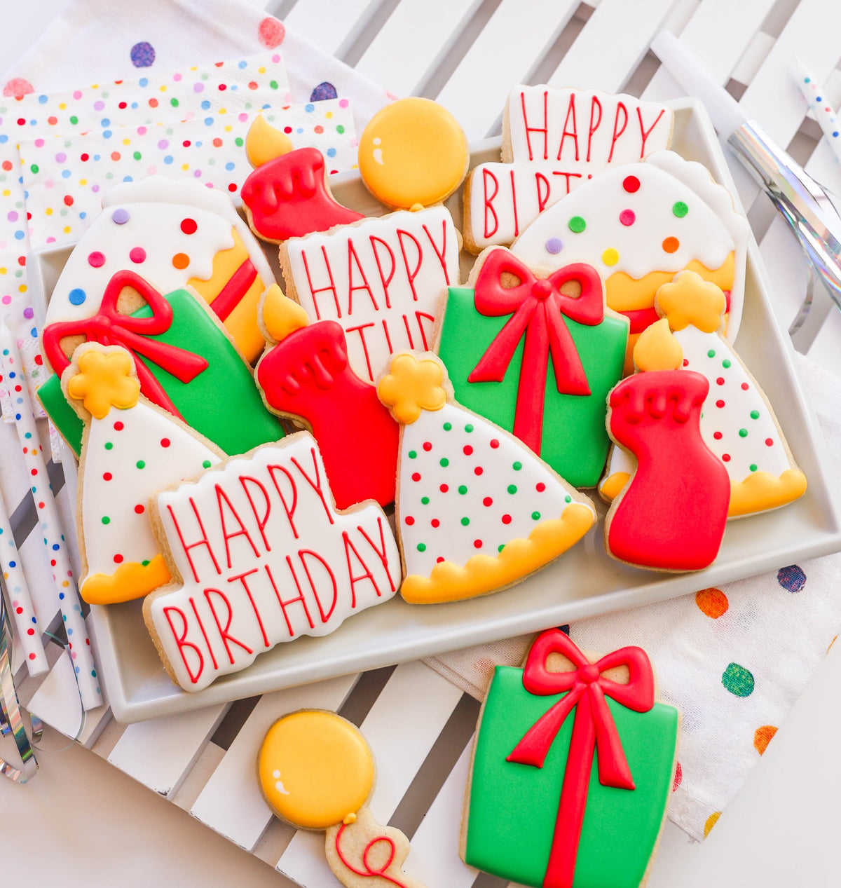 Verjaardagskoekjes met royal icing op een dienblad: taart met sprinkles, Happy Birthday-bordje, cadeautje, kaarsje, feesthoedje en ballon