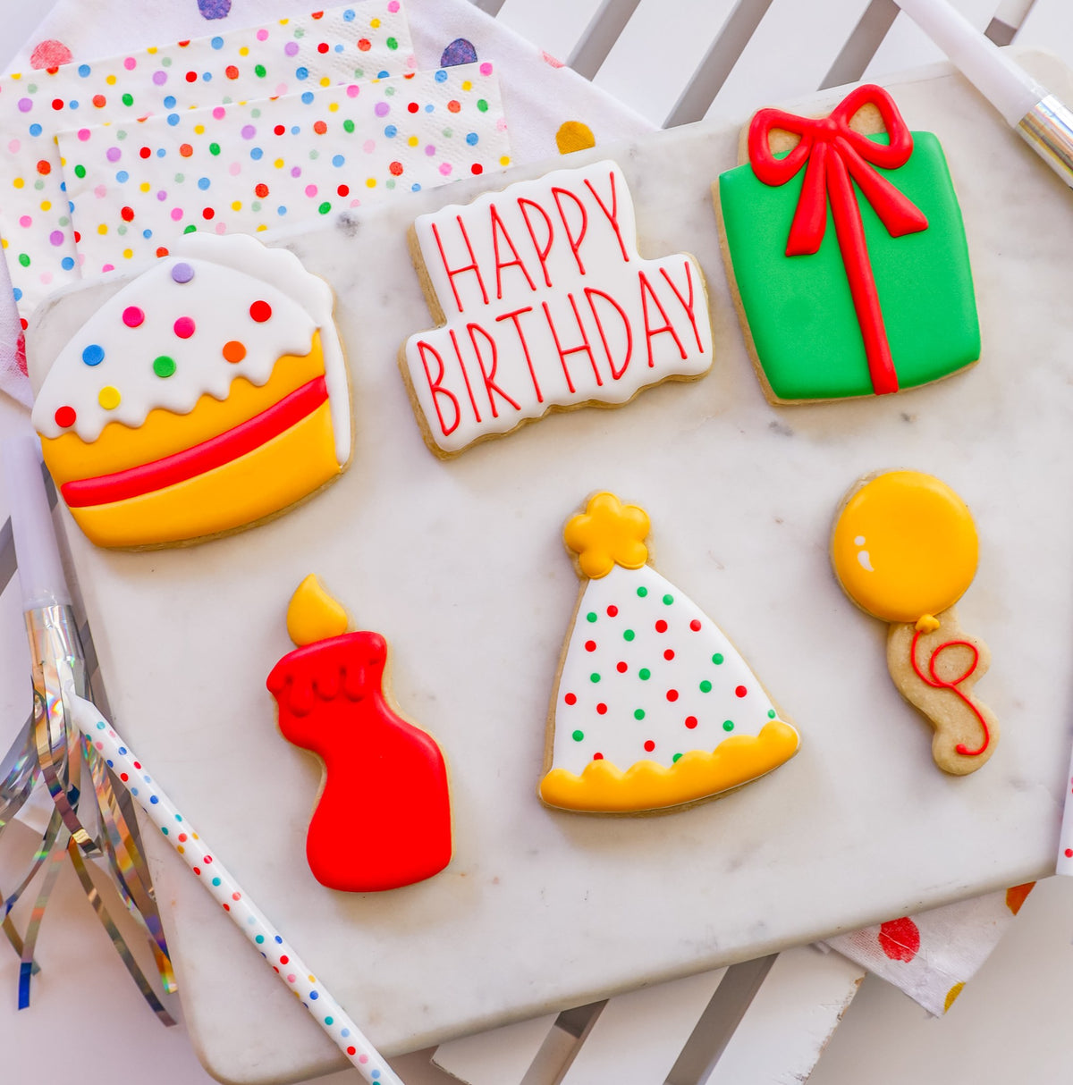 De zes Birthday workshopkoekjes naast elkaar: taart, Happy Birthday-bordje, groen cadeautje, rood kaarsje, feesthoedje en gele ballon